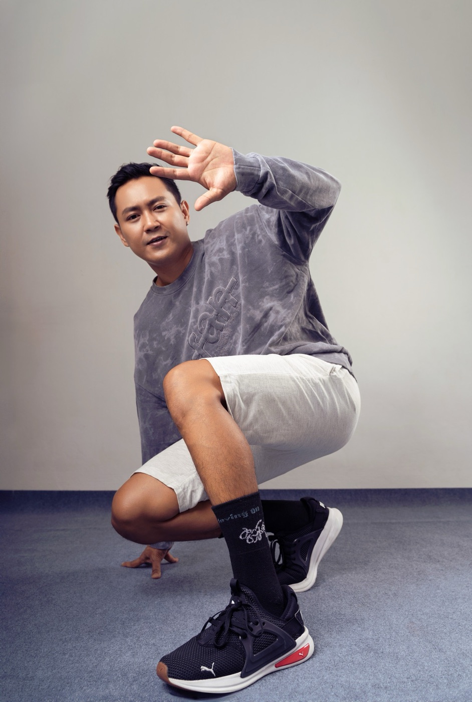 Model crouching with a hand raised, wearing black Keep Moving On crew socks and sneakers.