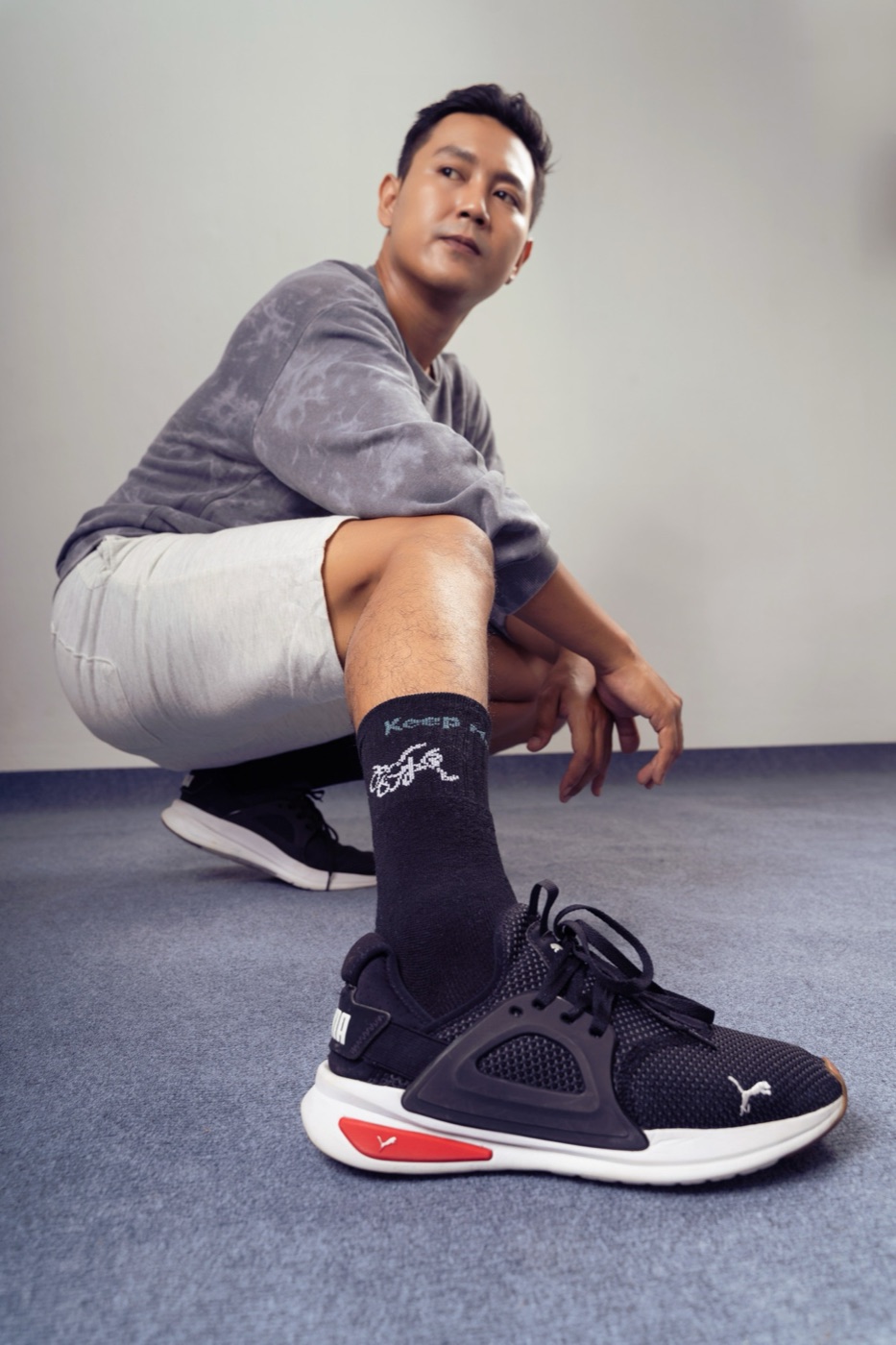 Model crouching in black Mid-Calf Crew socks and sneakers.