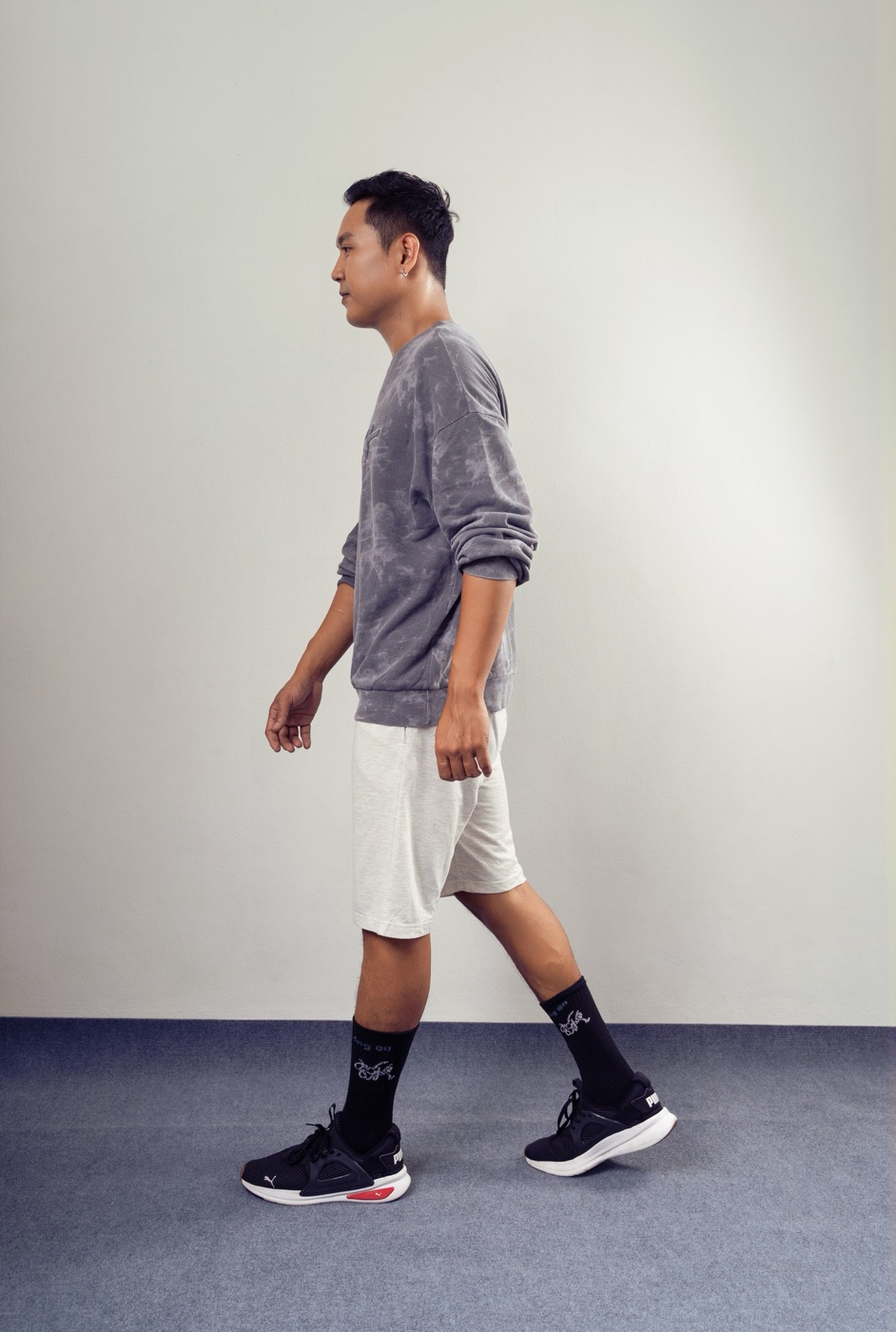 Side profile of a man walking in a white shirt, gray trousers, black socks and loafers.