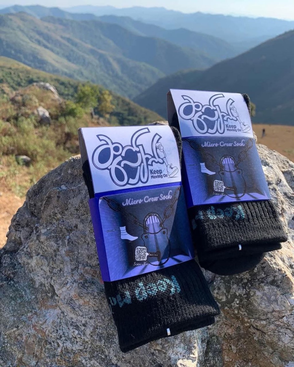 Two boxed pairs of Micro Crew socks resting on a rock above a mountain valley.