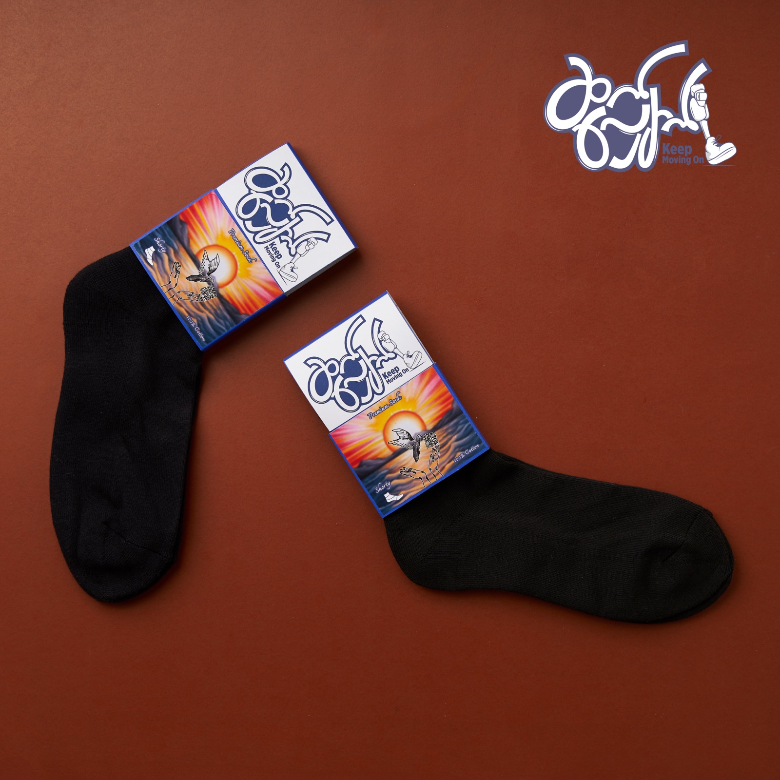 Gray Keep Moving On Shorty socks beside their artwork packaging boxes.